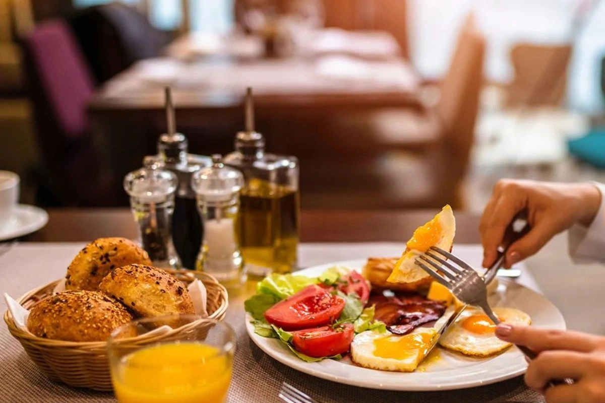 A person eating eggs and orange juice for breakfast in the restaurant caprichos