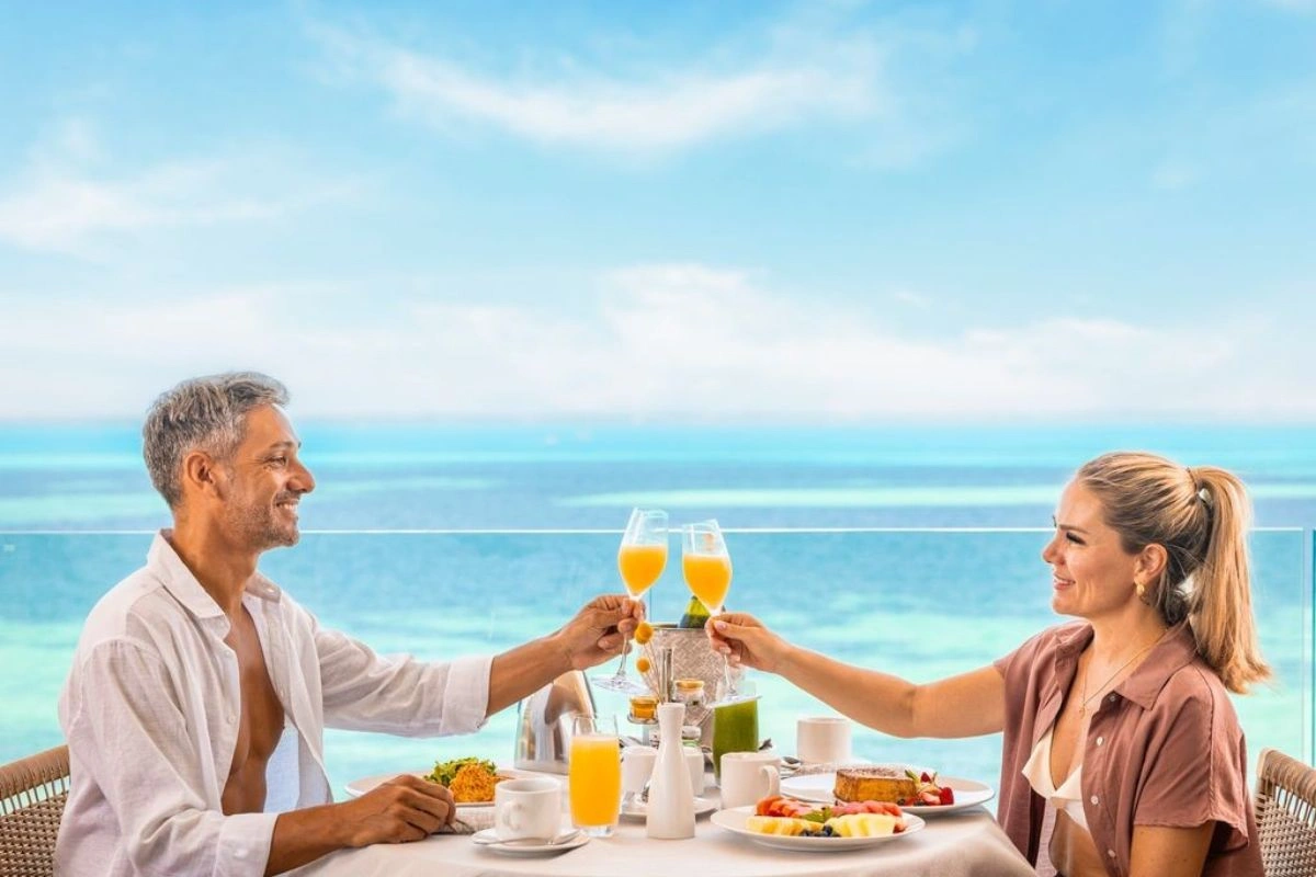 Couple having a romantic breakfast drinking a mimosa in front of the beautiful sea