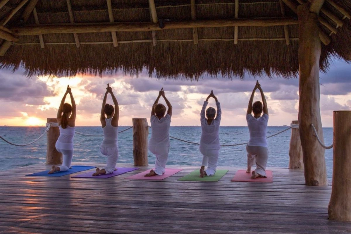 People doing yoga in front of the beach during the sunrise