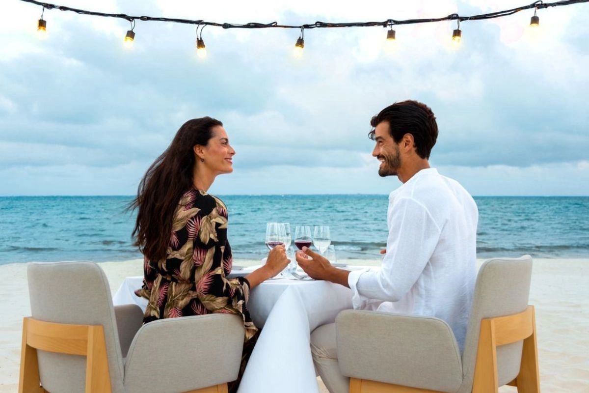 Couple celebrating anniversary with wine in front of the beach