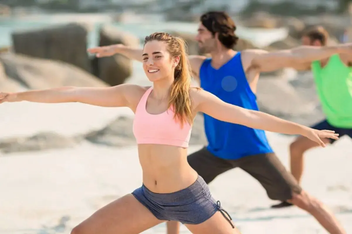 People doing yoga in the morning on the beach